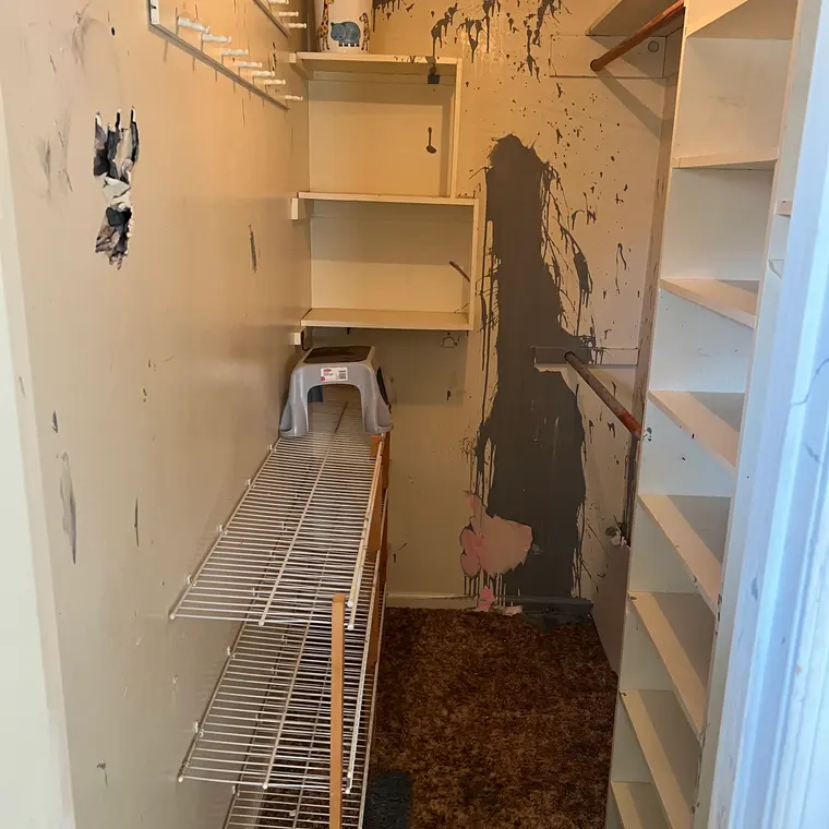 Damaged closet interior with torn walls and old wire shelving