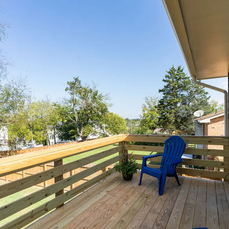 The rebuilt deck in fresh lumber with a new horizontal railing