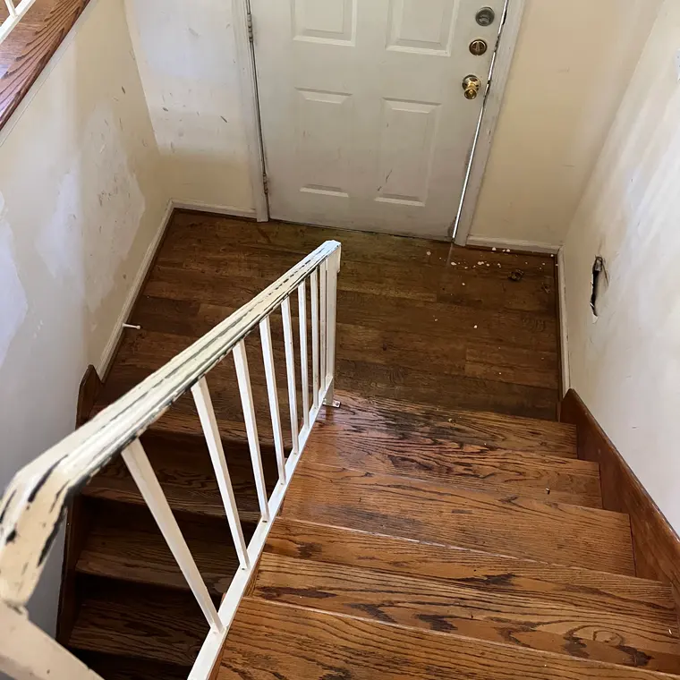 Split-foyer stairwell with an old white spindle railing and worn floors