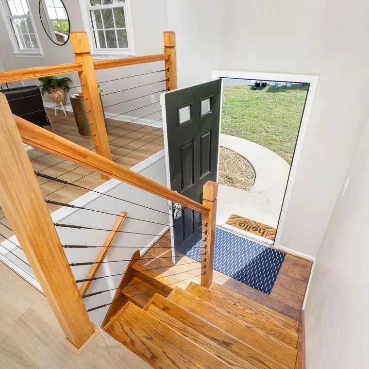 The renovated entry with a new wood-and-cable railing and refinished stairs