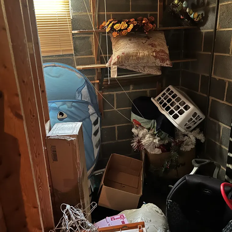Cluttered lower level with painted block walls used for storage