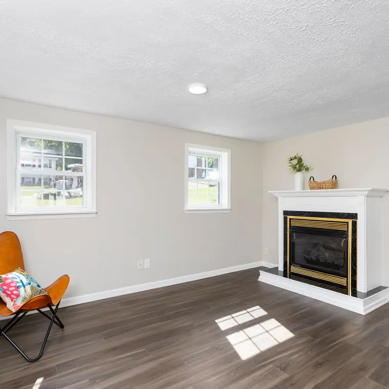The finished lower-level family room with a fireplace and new flooring