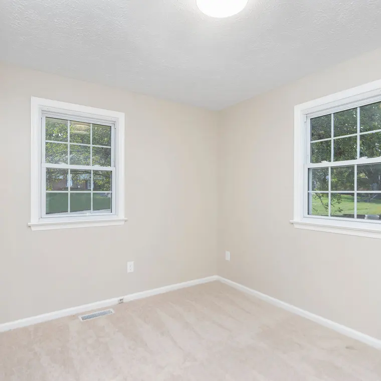 The same bedroom after renovation — finished walls, new carpet and trim